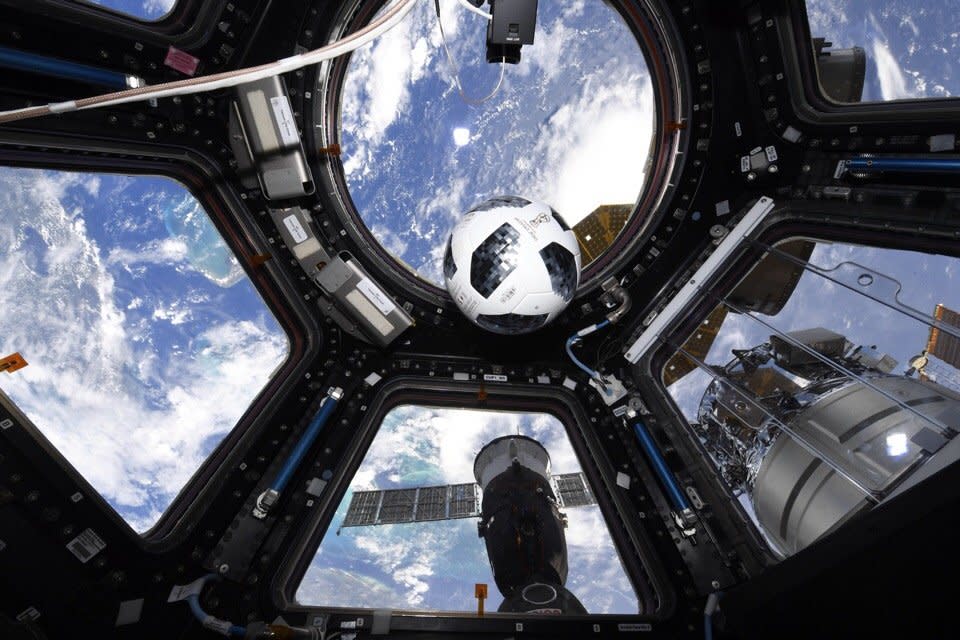 soccer ball floating in front of a multi-paned window in space with the earth behind