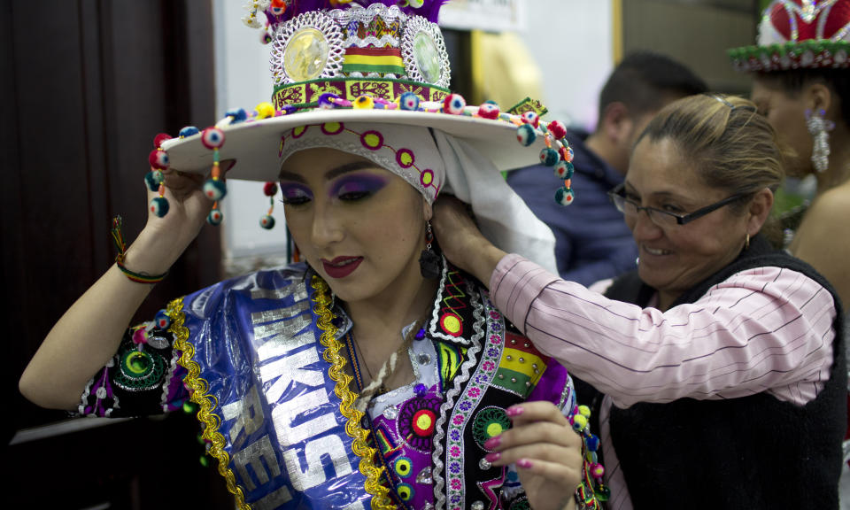 A woman helps a contestant with her outfit in preparation for the Queen of Great Power contest, in La Paz, Bolivia, Friday, May 24, 2019. The largest religious festival in the Andes choses its queen in a tight contest to head the Festival of the Lord Jesus of the Great Power, mobilizing thousands of dancers and more than 4,000 musicians into the streets of La Paz. (AP Photo/Juan Karita)
