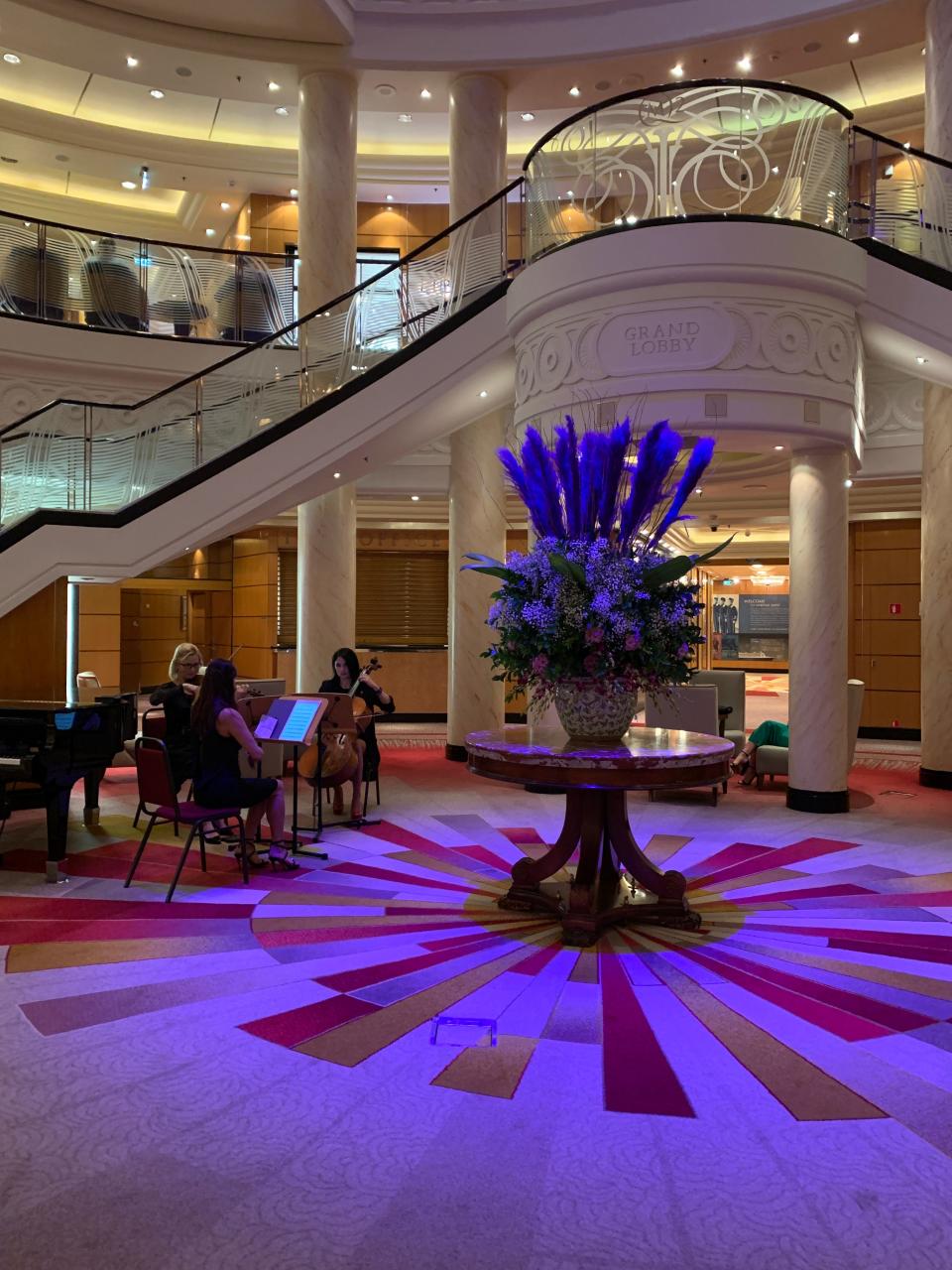 The Grand Lobby on board the Queen Mary 2 in January of 2024 during the crossing from New York to Southampton, UK., as a string trio plays.