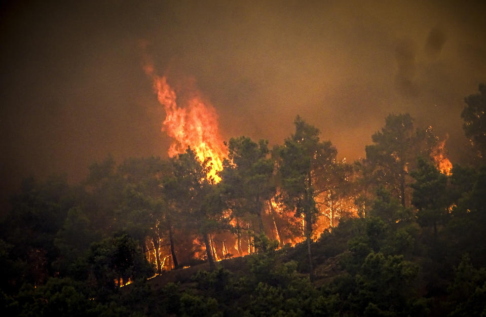 Flames rise during a forest fire on the island of Rhodes, Greece, Saturday, July 22, 2023. A large wildfire burning on the Greek island of Rhodes for a fifth day has forced authorities to order an evacuation of four locations, including two seaside resorts. (Argyris Mantikos/Eurokinissi via AP)