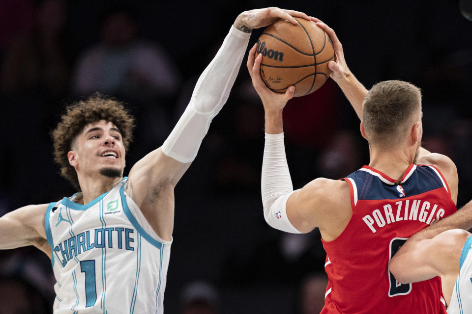 Charlotte Hornets guard LaMelo Ball (1) tries to block a shot from Washington Wizards center Kristaps Porzingis in the first half of an NBA preseason basketball game in Charlotte, N.C., Monday, Oct. 10, 2022. (AP Photo/Jacob Kupferman)