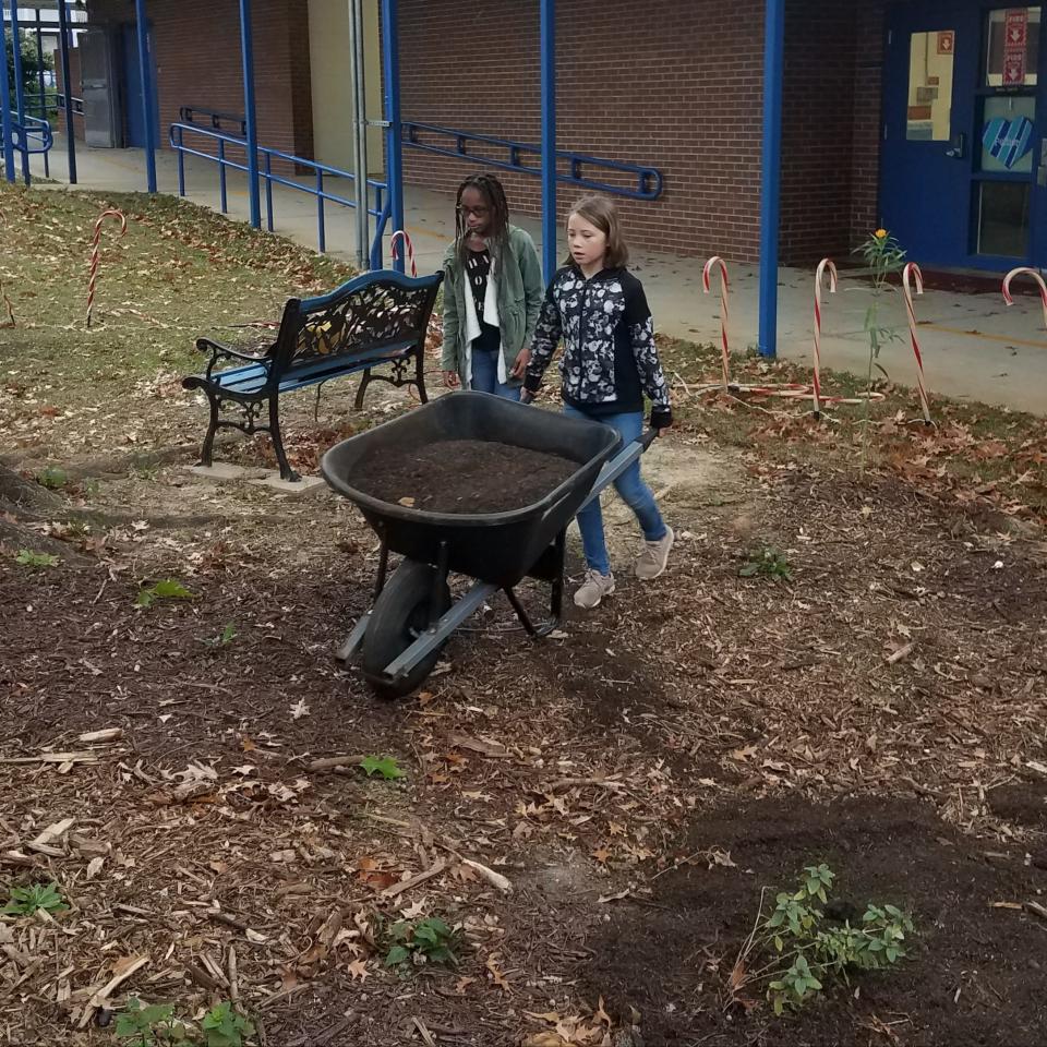 Students practice teamwork moving compost to the new garden.