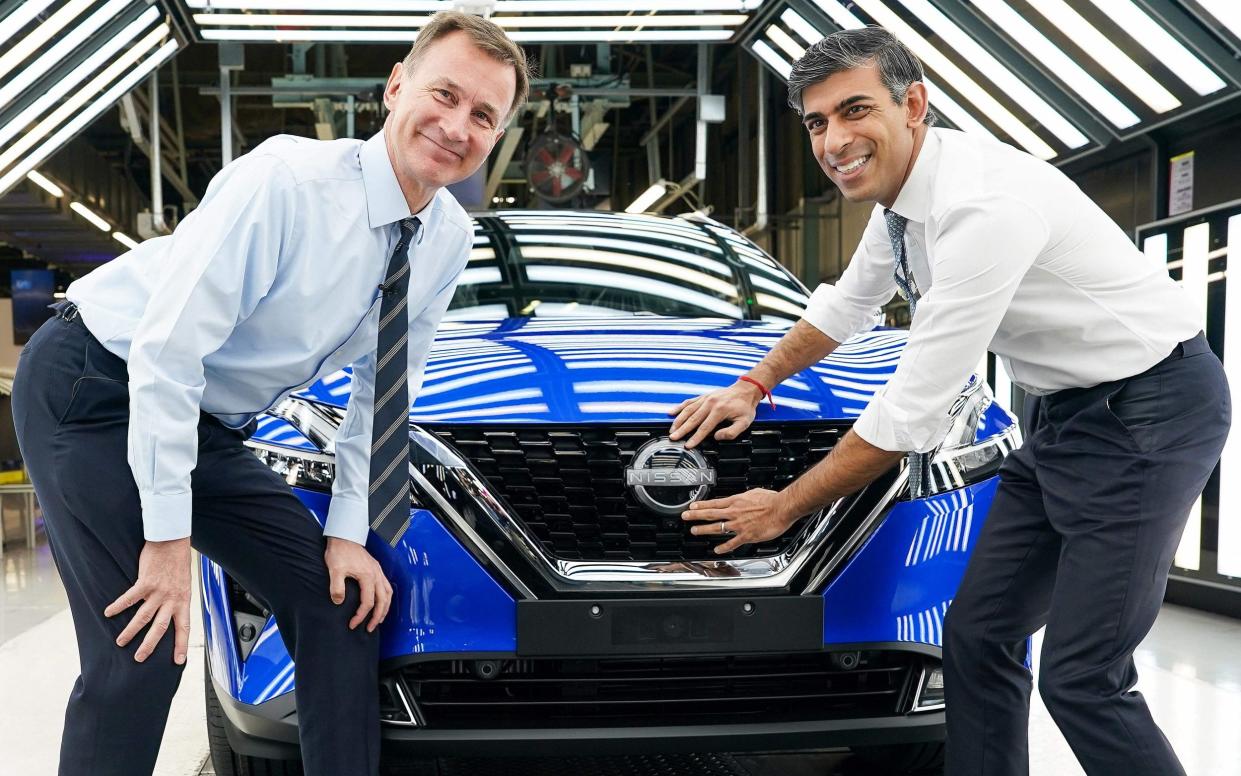 Britain's Prime Minister Rishi Sunak and Britain's Chancellor of the Exchequer Jeremy Hunt pose for a photograph as they attach a Nissan badge to the grill of a newly manufactured car during a visit to the Nissan production plant in Sunderland, north east England on November 24