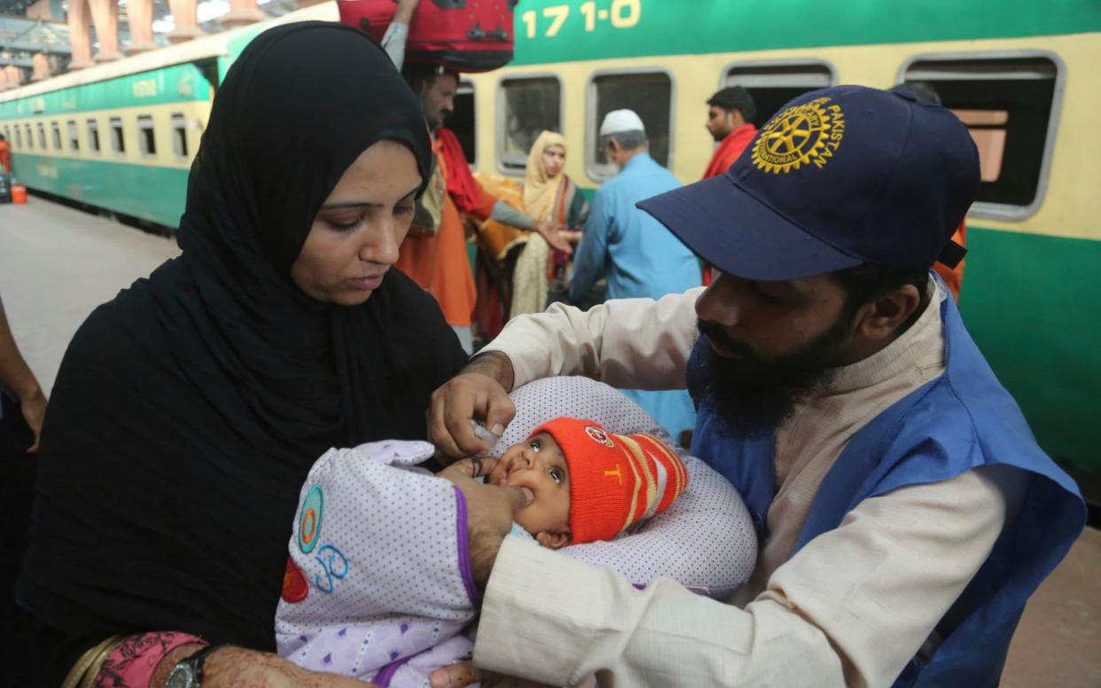 A health worker giving a polio vaccination to a child in Lahore railway station, Pakistan  - AP