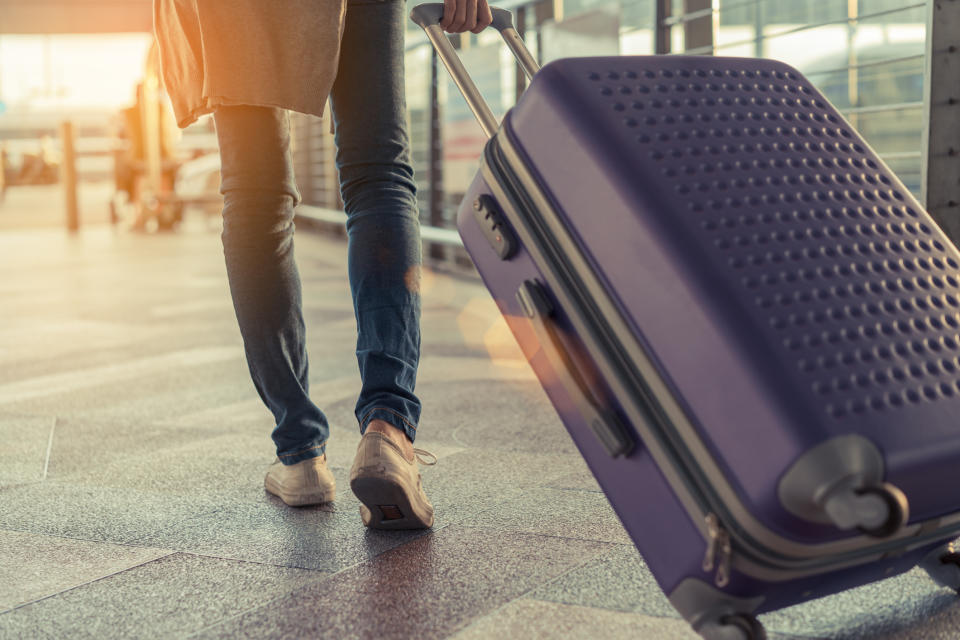 Man pulling suitcase behind him in an airport.