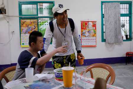 Chen Hong-zhi, 26, who suffers from short-term memory loss, talks to his friend at his neighbour's home in Beipu Old Street area in Hsinchu, Taiwan, August 17, 2018. REUTERS/Tyrone Siu