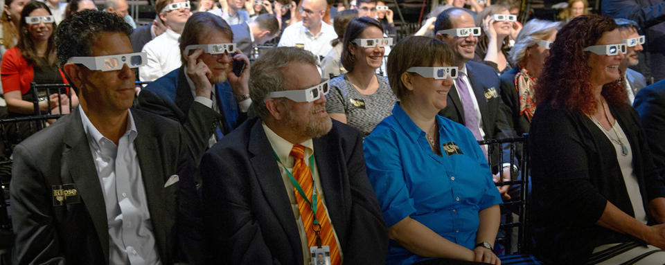 Audience members try on solar filter glasses during a total solar eclipse briefing, Wednesday, June 21, 2017 at the Newseum in Washington. <cite>NASA/Bill Ingalls</cite>