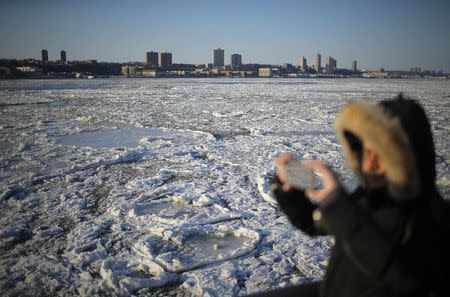 A man takes pictures of ice floes along the Hudson River in New York, February 20, 2015. REUTERS/Eduardo Munoz