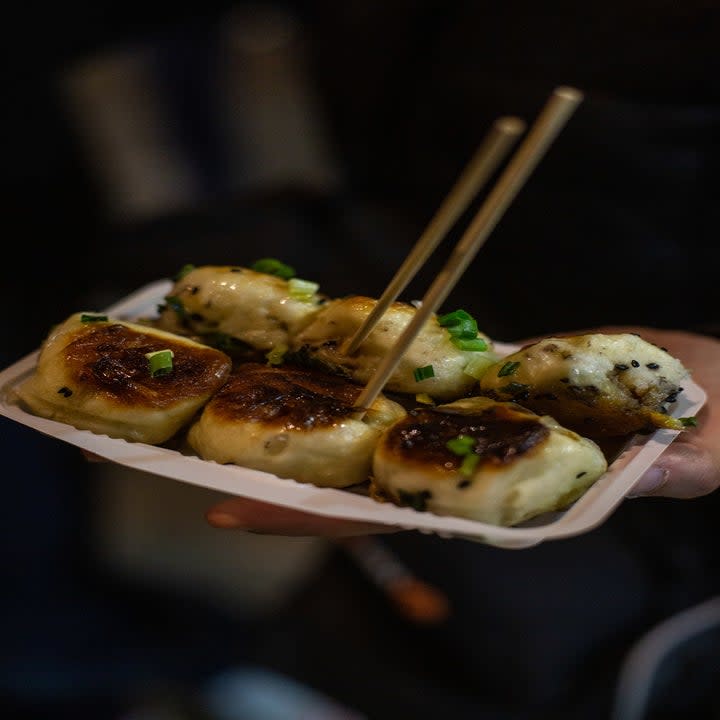 Pan fried dumplings with chopsticks.