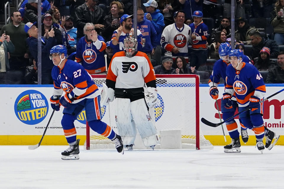 Philadelphia Flyers goaltender Carter Hart (79) waits as New York Islanders' Anders Lee (27), Oliver Wahlstrom (26) and Jean-Gabriel Pageau (44) skate past him after Lee scored a goal during the first period of an NHL hockey game Wednesday, Nov. 22, 2023, in Elmont, N.Y. (AP Photo/Frank Franklin II)