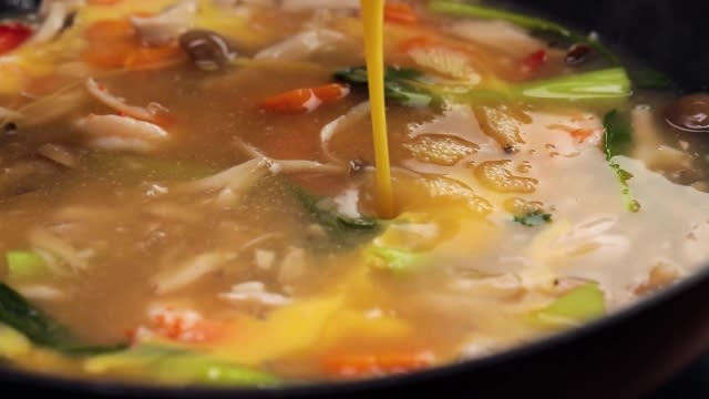 Pouring beaten eggs into seafood gravy