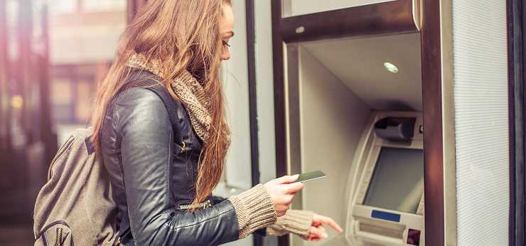 A young woman withdraws money from an ATM.