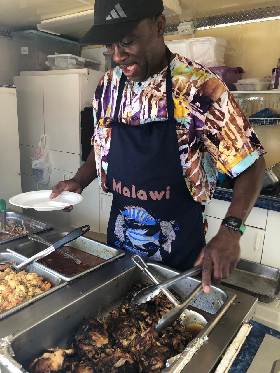 John Pangani serves up jerk chicken that he's made in the style and spices of his homeland, the African country of Malawi, on Saturday, Sept. 9, 2023, at Fusion Fest at Howard Park in South Bend.