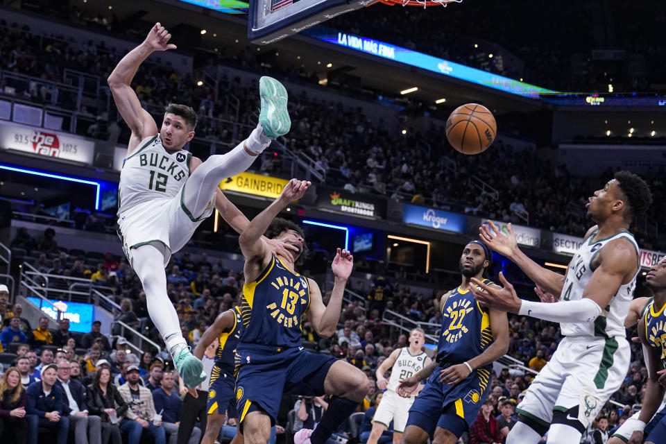 Milwaukee Bucks guard Grayson Allen (12) is fouled on a dunk by Indiana Pacers forward Jordan Nwora (13) during the second half of an NBA basketball game in Indianapolis, Wednesday, March 29, 2023. (AP Photo/Michael Conroy)