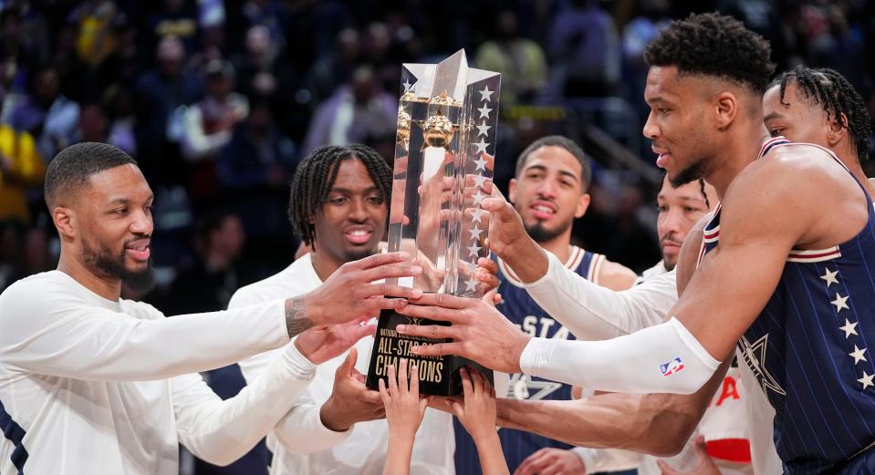 Eastern Conference guard Damian Lillard (0) of the Milwaukee Bucks and Eastern Conference forward Giannis Antetokounmpo (34) of the Milwaukee Bucks grab the trophy Sunday, Feb. 18, 2024, during the 73rd NBA All-Star game at Gainbridge Fieldhouse in downtown Indianapolis.