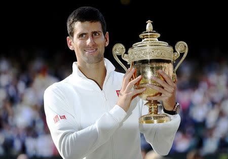 Novak Djokovic of Serbia holds the winners trophy after defeating Roger Federer of Switzerland in their men's singles final tennis match at the Wimbledon Tennis Championships, in London July 6, 2014. REUTERS/Stefan Wermuth