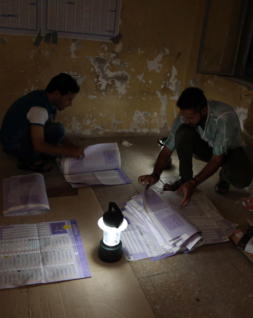Electoral workers count ballots under lamplight, due to a power cut, as polls close at a polling center in Baghdad, Iraq, Wednesday, April 30, 2014. Iraqis braved the threat of bombs and other violence to vote Wednesday in parliamentary elections amid a massive security operation as the country slides deeper into sectarian strife. (AP Photo/Karim Kadim)