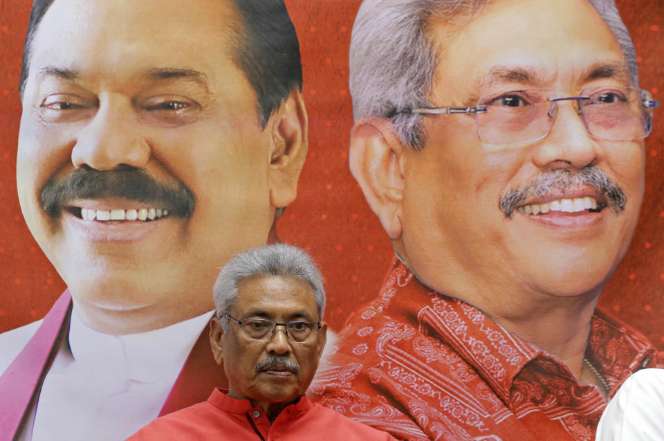 In this Nov. 6, 2019 photo, Sri Lankan presidential candidate and former defense chief Gotabaya Rajapaksa is seated next to a billboard carrying portraits of him self and his brother Mahinda at his residence in Colombo, Sri Lanka. Sri Lankans will be voting Saturday for a new president after weeks of campaigning that largely focused on national security and religious extremism in the backdrop of the deadly Islamic State-inspired suicide bomb attacks on Easter Sunday. (AP Photo/Eranga Jayawardena)