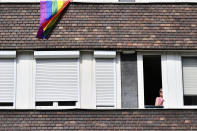 A rainbow flag hangs froma building as a woman watches participants in a gay pride parade in Budapest, Hungary, Saturday, July 24, 2021. Hungary's government led by right-wing Prime Minister Viktor Orban passed a law in June prohibiting the display of content depicting homosexuality or gender reassignment to minors, a move that has ignited intense opposition in Hungary while EU lawmakers have urged the European Commission to take swift action against Hungary unless it changes tack. (AP Photo/Anna Szilagyi)