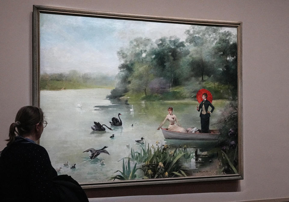 A visitor looks at the painting of Sarah Bernhardt and Louis Abbema on the lake of Bois de Boulogne painted by Louis Abbema, 1883, as part of the "Sarah Bernhardt, and the woman created the star" exhibition at the Petit Palais museum in Paris, Friday, April 28, 2023. Inside Paris’ Petit Palais museum, the public is now discovering the madcap jigsaw puzzle of gothic stories, costumes, recordings, films, photos, jewels, sculptures, and personal objects for the first time together that made the unclassical beauty the object of fascination from Berlin, to London and New York. (AP Photo/Michel Euler)