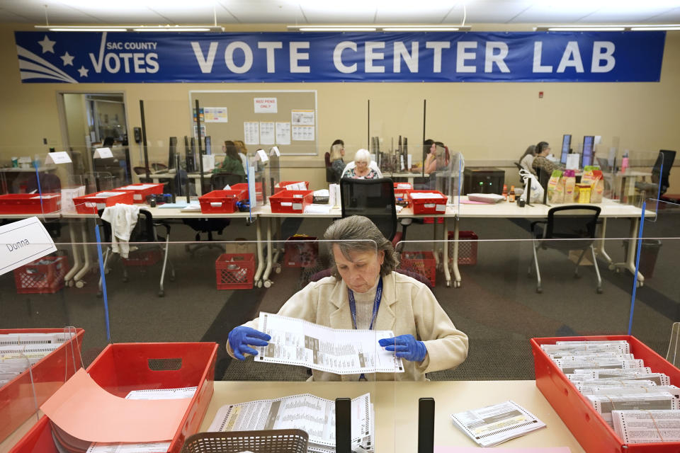 FILE - Election worker Donna Young inspects a mail-in ballot for damage at the Sacramento County Registrar of Voters in Sacramento, Calif., June 3, 2022. Unlike in many other countries, elections in the U.S. are highly decentralized, complex and feature a long list of races on the ballot, from president or Congress all the way down to local ballot measures or town council seats. Rules also vary greatly by state. Some give local election offices several weeks before Election Day to process mailed ballots, which includes steps that may include checking signatures or ID information. (AP Photo/Rich Pedroncelli, File)