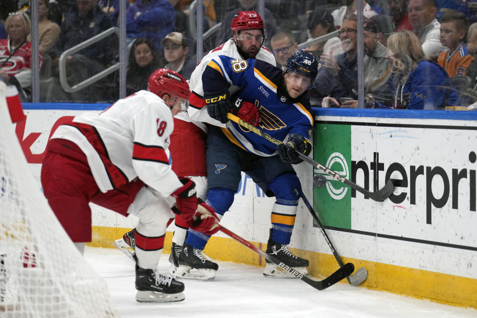 St. Louis Blues' Scott Perunovich (48) passes as Carolina Hurricanes' Jack Drury (18) and Stefan Noesen (23) defend during the third period of an NHL hockey game Friday, April 12, 2024, in St. Louis. (AP Photo/Jeff Roberson)