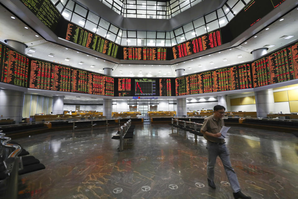 An investor walks in front of stock trading boards at a private stock market gallery in Kuala Lumpur, Malaysia, Thursday, July 18, 2019. Asian stock markets on Thursday followed Wall Street lower after President Donald Trump reignited trade fears by saying he could impose more tariffs on Chinese imports. (AP Photo/Vincent Thian)