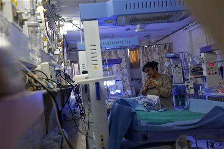 Rekha Patel, 42, from Britain, looks at her week-old-baby girl Gabriella, at the Akanksha IVF centre in Anand town, about 70 km (44 miles) south of the western Indian city of Ahmedabad August 24, 2013. REUTERS/Mansi Thapliyal