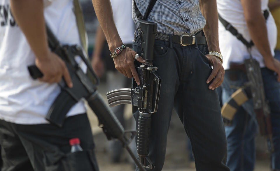 Armed men belonging to the Self-Defense Council of Michoacan (CAM) stand guard at a checkpoint set up by the vigilante group in La Mira on the outskirts of the seaport of Lazaro Cardenas in western Mexico, Friday, May 9, 2014. Starting Saturday, a federal commissioner now in charge of the violence-plagued state hopes to end the “wild west” chapter of the vigilante movement, in which civilians went to battle against cartel members for towns in the rich farming area called the “Tierra Caliente,” or Hot Land. (AP Photo/Eduardo Verdugo)