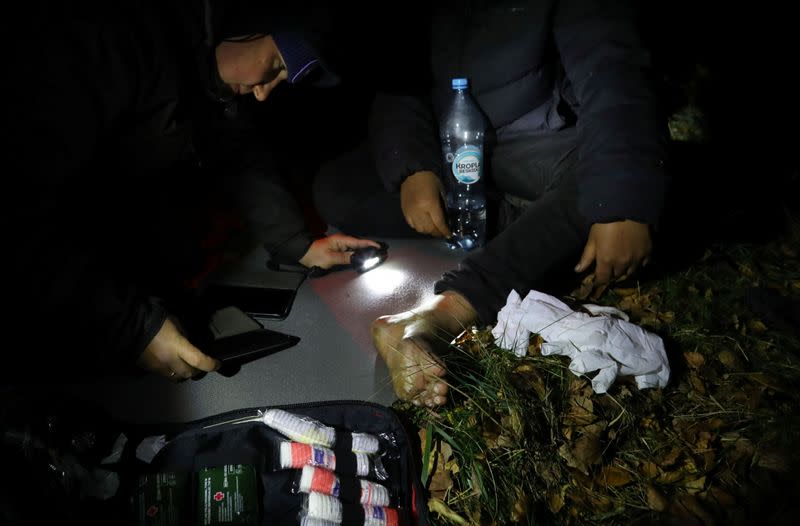 Bystrianin of the Ocalenie foundation covers the wound of the migrant after he crossed Belarusian-Polish border in the woods near Sokolka