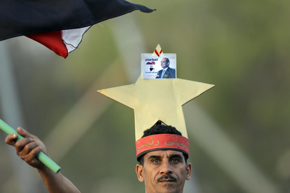 An Egyptian supporter of presidential hopeful, ex-military chief Abdel-Fattah el-Sissi, waves a national flag as he wears a star, el-Sissi's presidential election symbol, during a campaign rally in Cairo, Egypt, Saturday, May 10, 2014. In the first rally to back el-Sissi’s bid for presidency since the campaigning began last week, supporters of the former military chief organized an evening event in the gardens of a Cairo conference center, drawing several thousands -- a much smaller crowd than originally announced. (AP Photo/Amr Nabil)