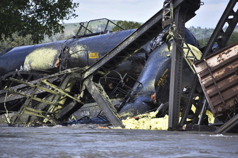 Several train cars are immersed in the Yellowstone River after a bridge collapse near Columbus, Mont., on Saturday, June 24, 2023. The bridge collapsed overnight, causing a train that was traveling over it to plunge into the water below. Authorities on Sunday were testing the water quality along a stretch of the Yellowstone River where mangled cars carrying hazardous materials remained after crashing into the waterway. (AP Photo/Matthew Brown)