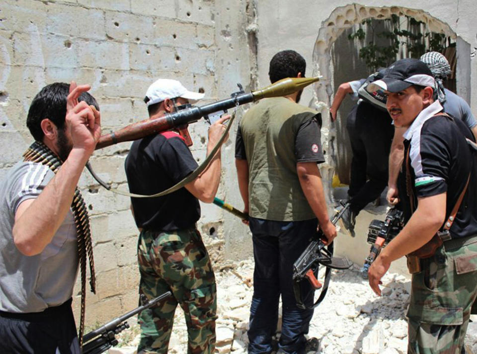 FILE - In this file photo released on Monday, June 18, 2012, by the anti-government activist group Rebels Battalion of Baba Amro, which has been authenticated based on its contents and other AP reporting, Syrian rebels hold their weapons as they prepare to fight against Syrian troops, in Homs province, Syria. Syria's government and rebels agreed to a cease-fire on Friday, May 2, 2014, in the battleground city of Homs to allow hundreds of fighters holed up in its old quarters to evacuate, a deal that will bring the country's third–largest city under control of forces loyal to President Bashar Assad. (AP Photo/Rebels Battalion of Baba Amro, File)