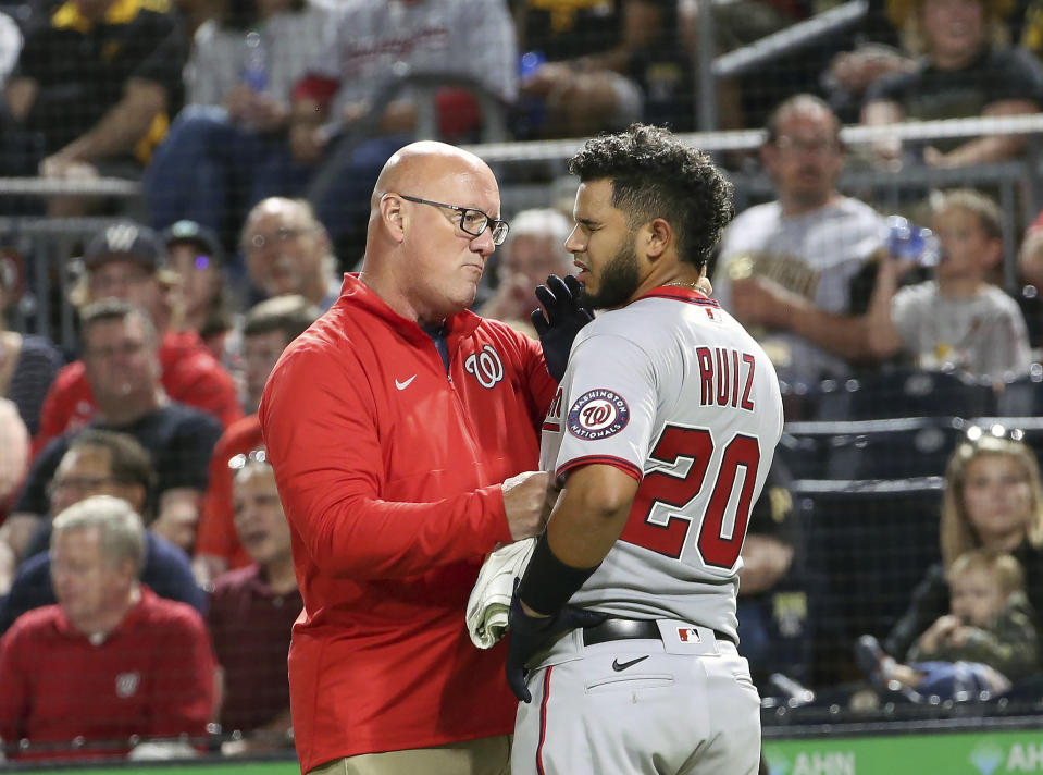Washington Nationals' Keibert Ruiz (20) is checked out by athletic trainer Paul Lessard after being hit by a pitch in the sixth inning of a baseball game against the Pittsburgh Pirates, Saturday, Sept. 11, 2021, in Pittsburgh. (AP Photo/Rebecca Droke)