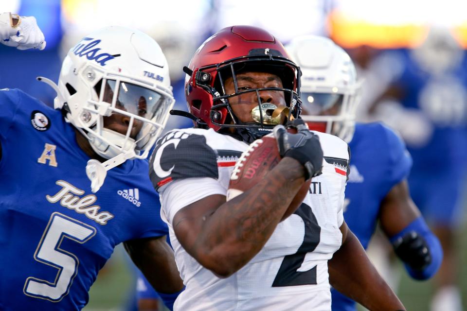 Cincinnati's Corey Kiner runs away from Tulsa defenders during the first half of an NCAA college football game in Tulsa, Okla., Saturday, Oct. 1, 2022. (AP Photo/Dave Crenshaw)