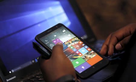 A Microsoft delegate checks applications on a smartphone during the launch of the Windows 10 operating system in Kenya's capital Nairobi, July 29, 2015. REUTERS/Thomas Mukoya