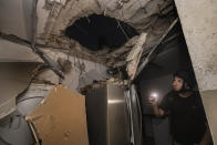 Un hombre israelí inspecciona los daños en una casa alcanzada por un cohete lanzado desde la Franja de Gaza, en Ashkelon, en el sur de Israel, el miércoles 12 de mayo de 2021. (AP Foto/Tsafrir Abayov)