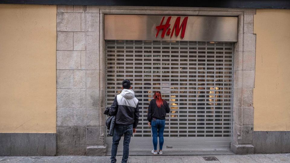 Passanten stehen vor einer geschlossenen H&M-Filiale.