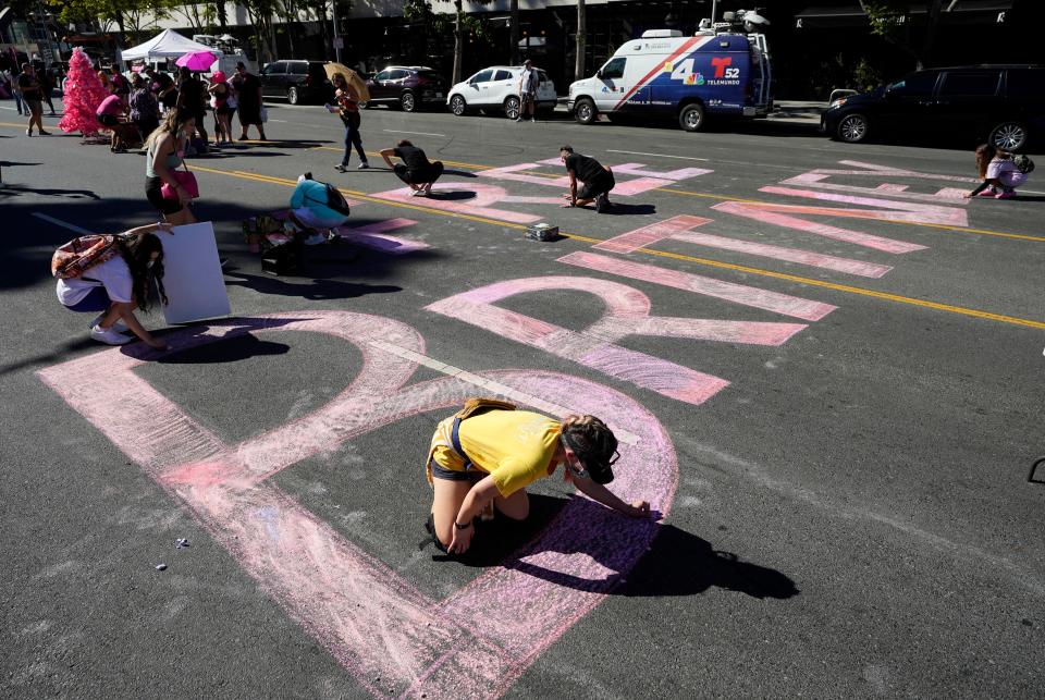 Stacy Moffatt, of Costa Mesa, Calif., bottom, and other Britney Spears supporters color in a "Free Britney" message on Grand Ave. outside the pop star's Nov. 12 hearing concerning her conservatorship in Los Angeles.
