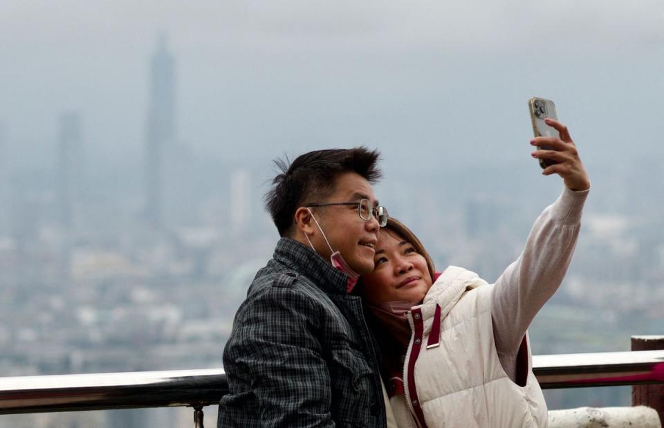 A couple takes a selfie picture with Taipei 101 building in the background from the Bidhanyen Taoist Temple in Taipei to mark the lunar new year (AFP via Getty Images)