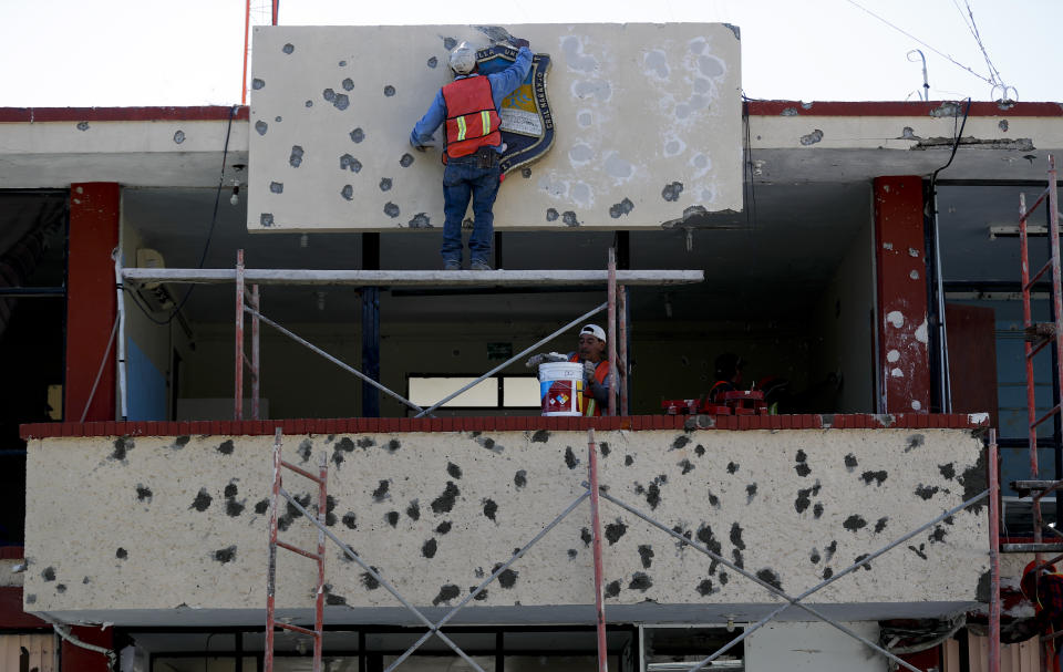 Trabajadores reparando la fachada del ayuntamiento, lleno de agujeros de bala, en Villa Unión, México, el lunes 2 de diciembre de 2019. (AP Foto/Eduardo Verdugo)