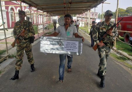 A member of polling staff guarded by security personnel carries a box containing postal ballots for counting in the northeastern Indian city of Agartala May 16, 2014. REUTERS/Jayanta Dey