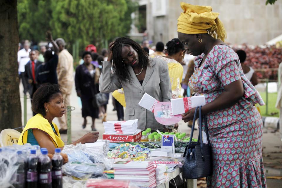 A woman sells envelopes for tithe offerings before a church service at the Living Faith Church, also known as the Winners' Chapel, in Ota district, Ogun state, some 60 km (37 miles) outside Nigeria's commercial capital Lagos September 28, 2014. Hundreds of millions of dollars change hands each year in Nigeria's popular Pentecostal "megachurches", which are modelled on their counterparts in the United States. Some of these churches can hold more than 200,000 worshippers and, with their attendant business empires, they constitute a significant section of the economy, employing tens of thousands of people and raking in tourist dollars, as well as exporting Christianity globally. To match Insight NIGERIA-MEGACHURCHES/ Picture taken September 28, 2014. REUTERS/Akintunde Akinleye (NIGERIA - Tags: RELIGION BUSINESS)