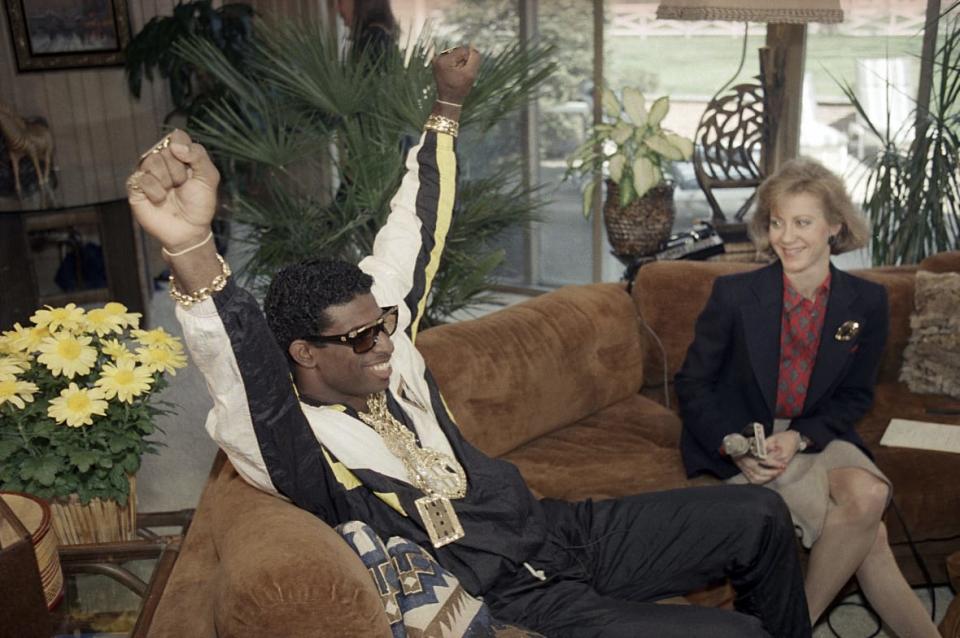 Florida State’s Deion Sanders, left, reacts as he sits with television reporter Andrea Kremer, at his agent’s suburban home in Winnetka, Ill., April 23, 1989. Sanders was selected by the Atlanta Falcons in the first round of the NFL draft. Sanders became the NFL draft’s first fashion icon by accessorizing a black and white track suit with a loads of sparkling gold jewelry and dark shades. (AP Photo/David Banks, File)