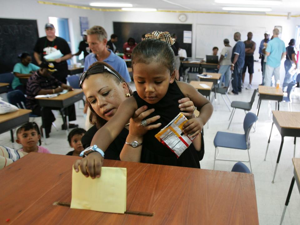 A woman holds up her child to cast a yellow ballot in the U.S. Virgin Islands.