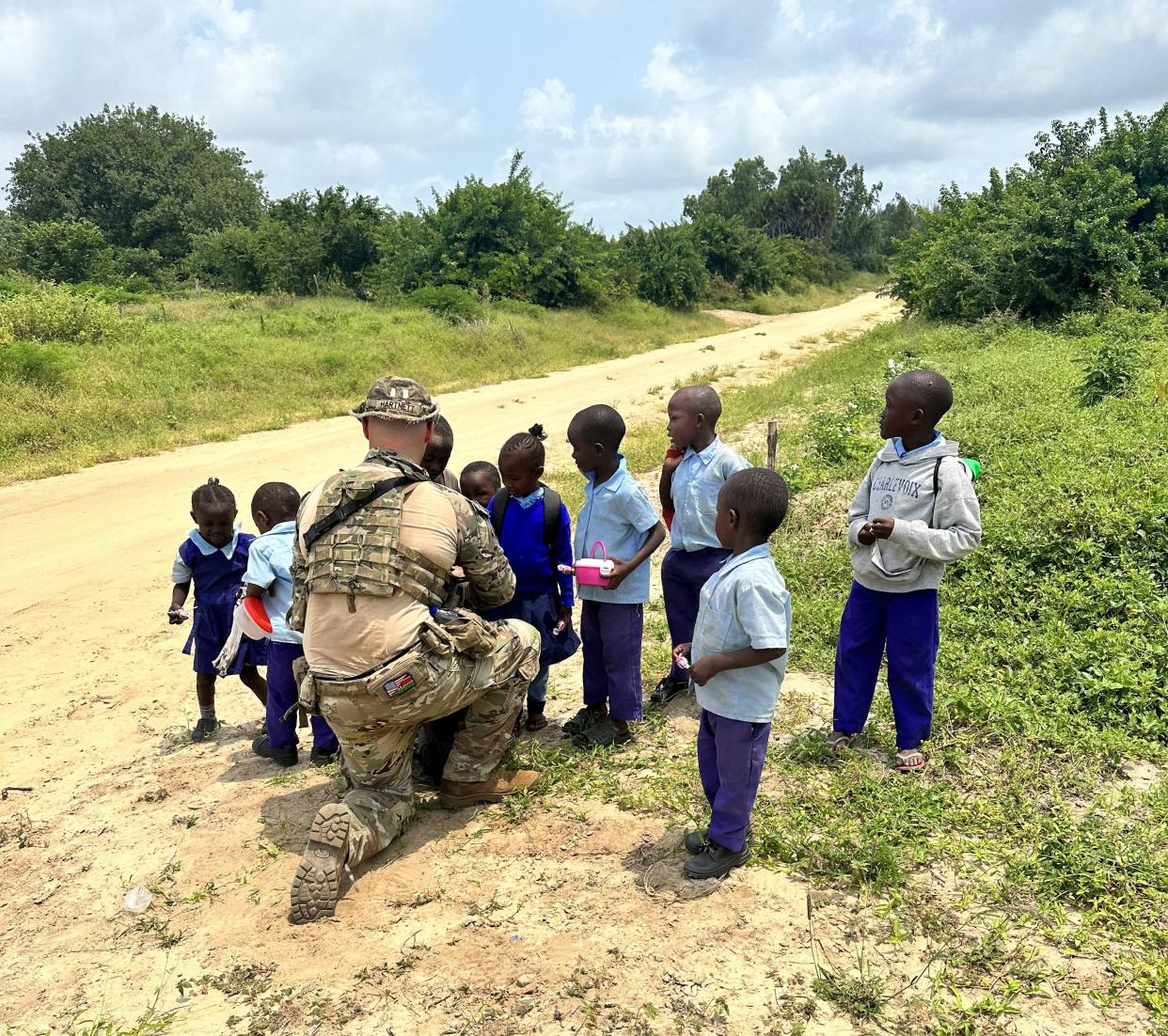 A member of the Indiana National Guard gives out sweets to local children near Camp Simba, Kenya, in 2023 as part of Operation Enduring Freedom.
