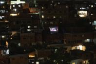 The film Aladdin is projected on a screen set up on the roof of a home, center right, in the Petare neighborhood of Caracas, Venezuela, late Monday, June 1, 2020. A neighborhood group called The Download Zone set up the movie as a free entertainment option for families cooped up since mid-March under the COVID-19 quarantine. (AP Photo/Ariana Cubillos)