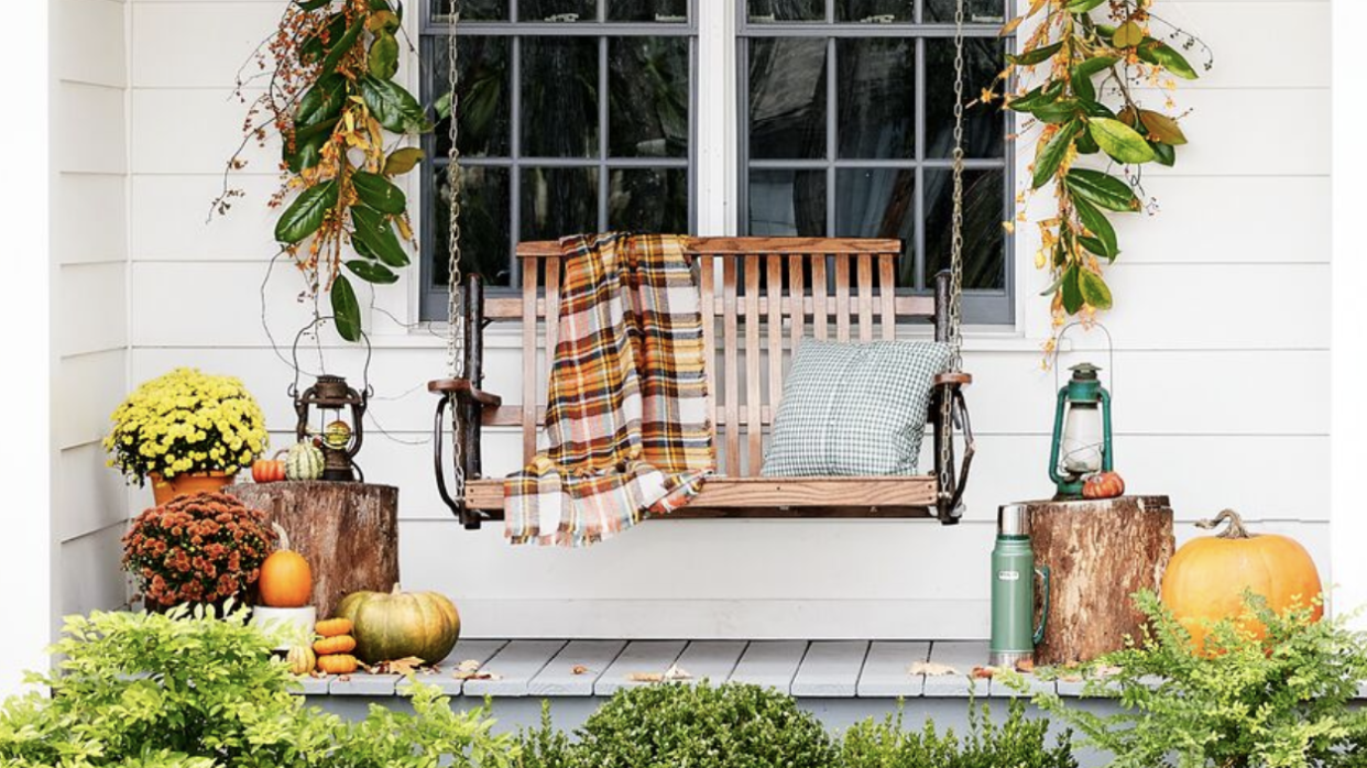 fall porch with a rustic swing and plaid blanket