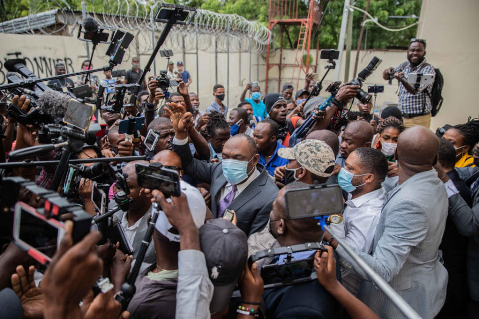 Former senator Youri Latortue leaves the courthouse on Monday flanked by his bodyguard, surrounded by media.