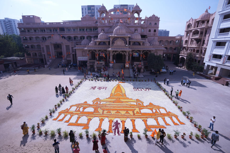 People looks at a huge floral design made to celebrate opening of a temple dedicated to Hindu deity Lord Ram in Ayodhya, in Ahmedabad, India, Monday, Jan. 22, 2024. (AP Photo/Ajit Solanki)